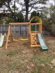 An Outdoor Living backyard play set with a slide and swings.